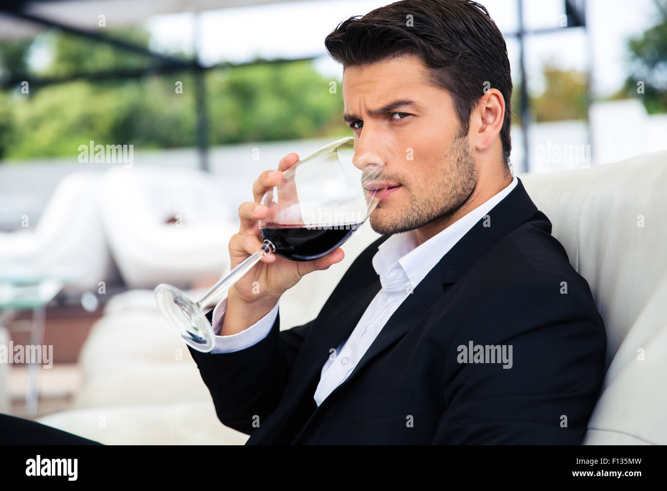 Confident young man drinking wine in restaurant Stock Photo - Alamy