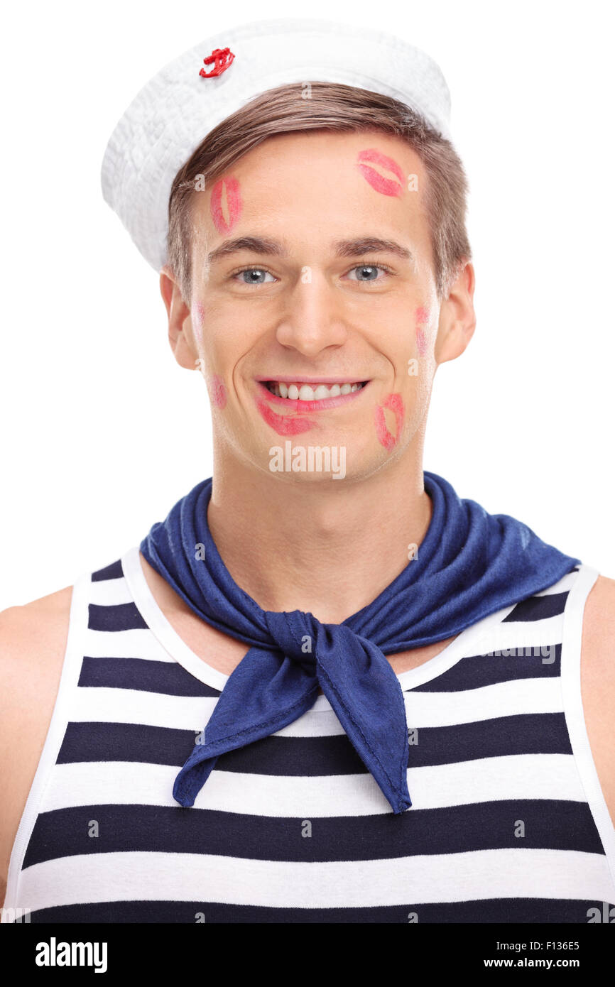 Vertical shot of a joyful male sailor covered in lipstick kiss marks looking at the camera and smiling Stock Photo