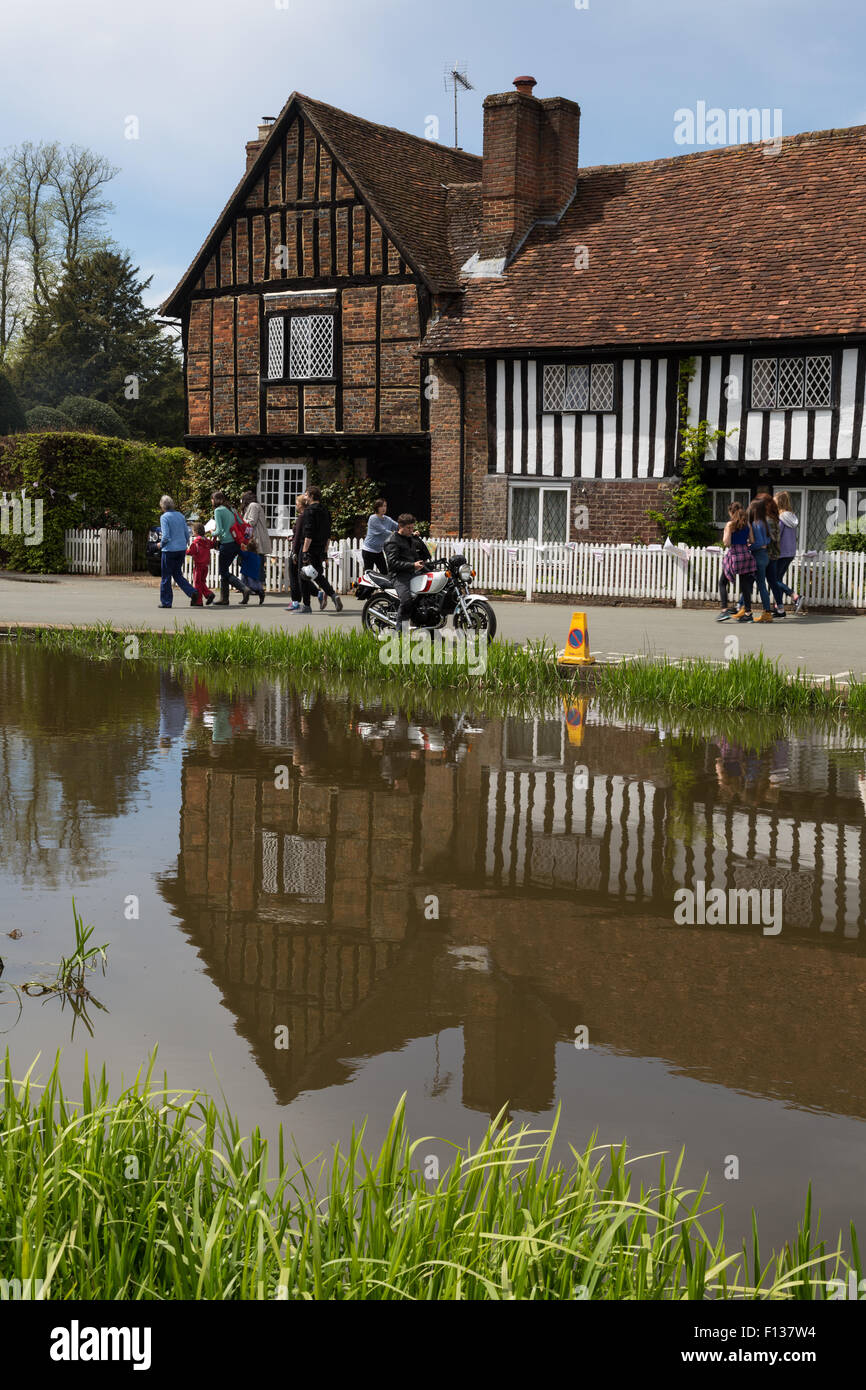 People visit a busy local village fete around a pond in front of a timbered building in Ashridge, England Stock Photo