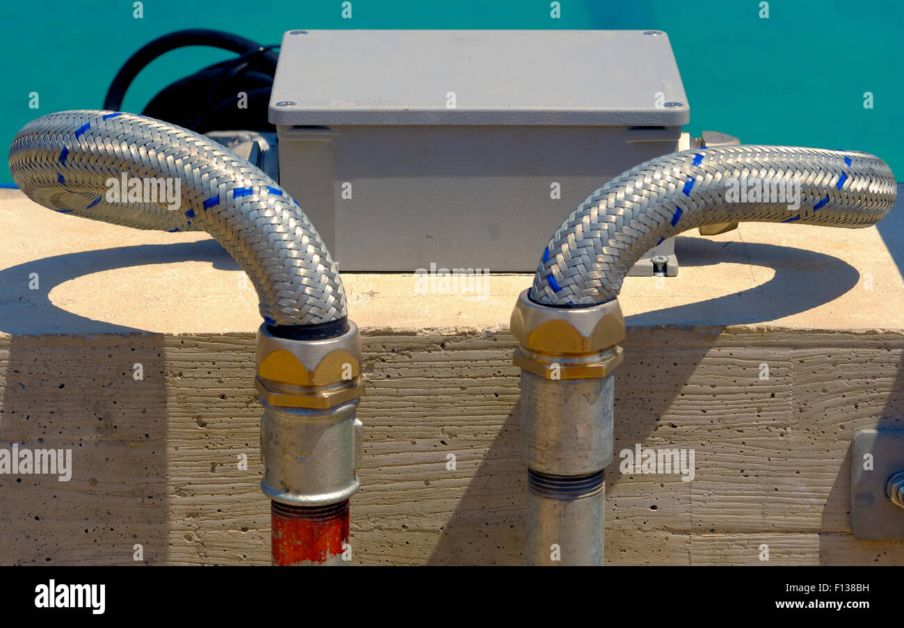 Galvanized steel tubes mounted on a concrete wall with its stopcocks Stock Photo