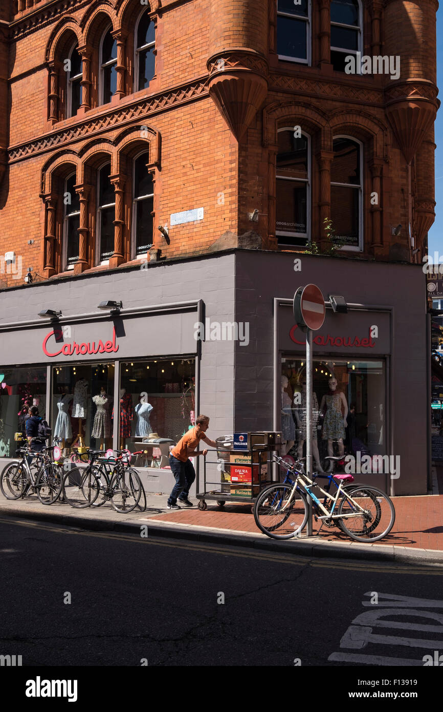 Delivery man pushing cart laden with beer barrels and crates of
