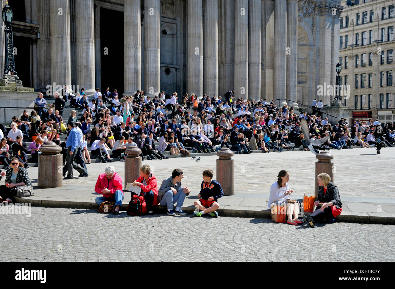London, England, UK. People sitting in the sun on the steps of St Paul's Cathedral Stock Photo