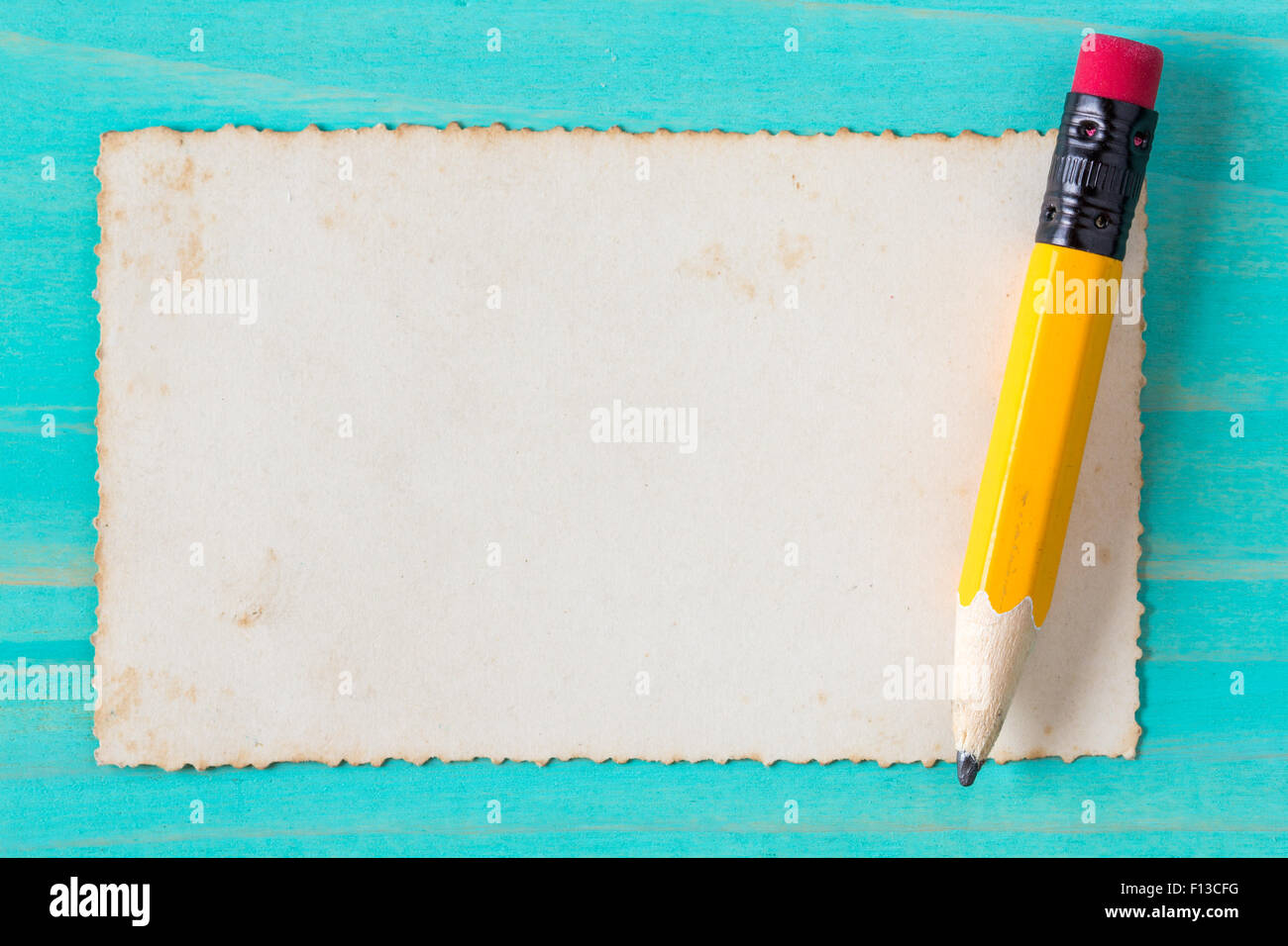 Yellow pencil with old paper on the blue wood surface Stock Photo