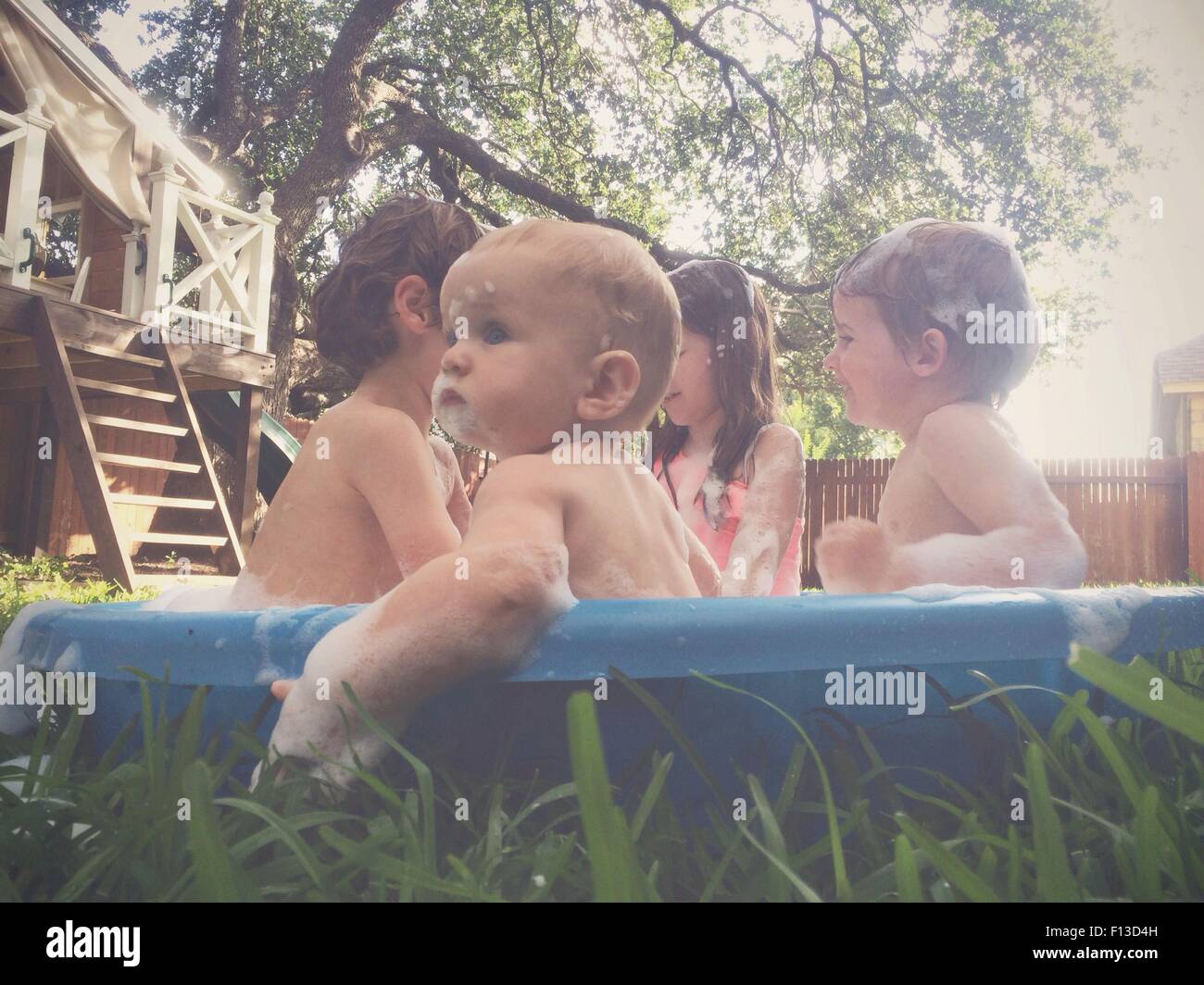 Children bathing and playing in an outdoor bath tub in the garden Stock Photo