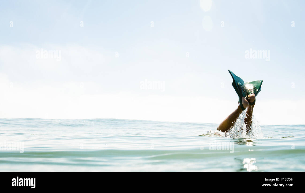 Human legs with flippers sticking out of the sea Stock Photo