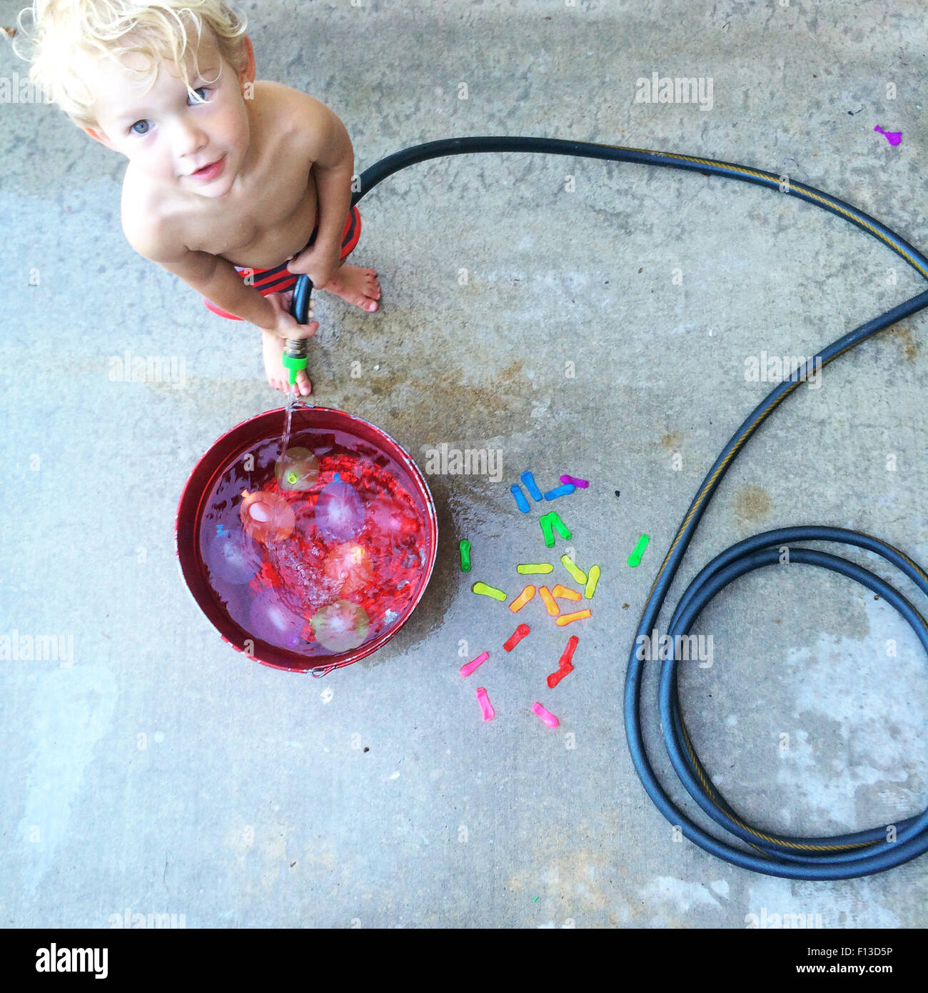 Toddler filling a bucket with water Stock Photo