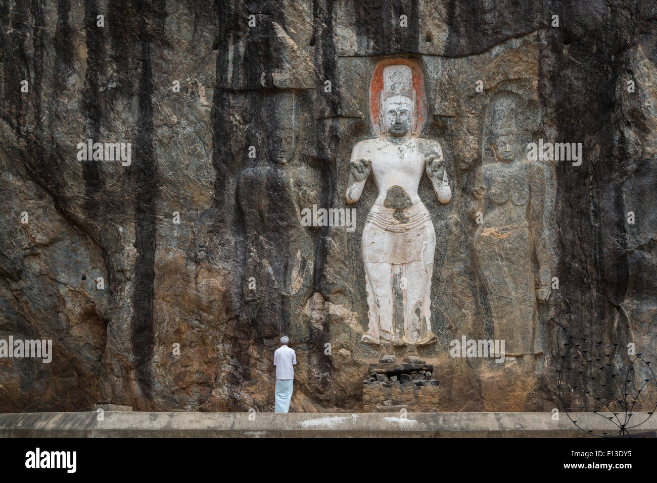 Man worshiping in front of rock sculpture, Sri Lanka Stock Photo