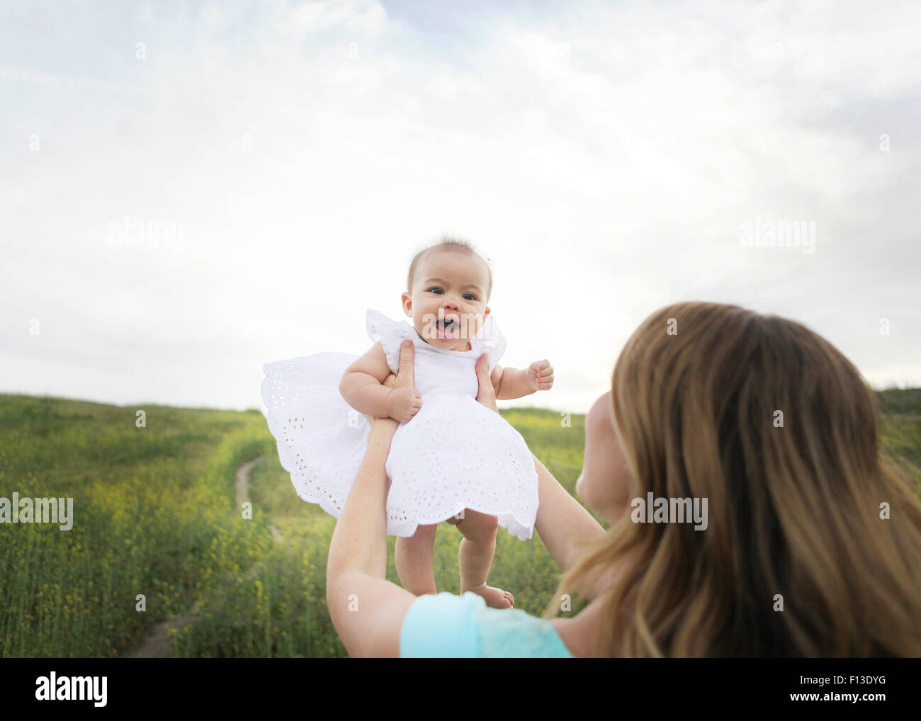 Mother lifting baby girl in the air Stock Photo