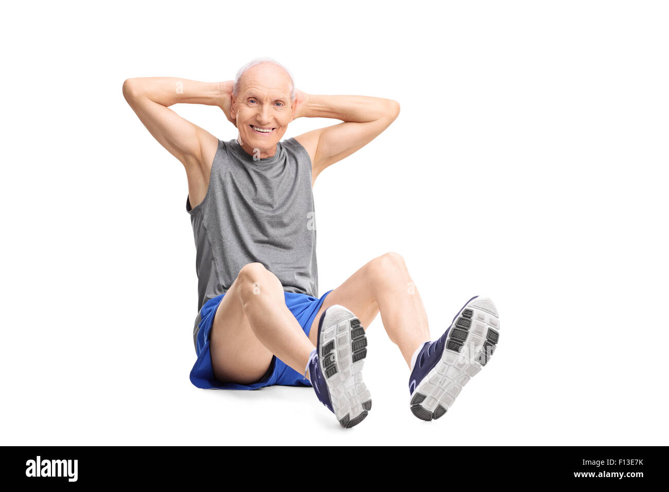 Active senior man in sportswear doing stomach crunches and looking at the camera isolated on white background Stock Photo