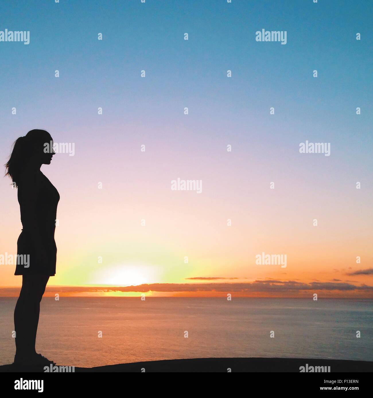 Silhouette of a woman looking out to sea at sunset, Tenerife, Canary Islands, Spain Stock Photo