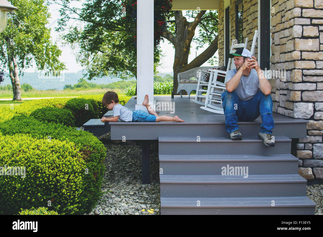 Man sitting on porch steps looking at son Stock Photo Alamy