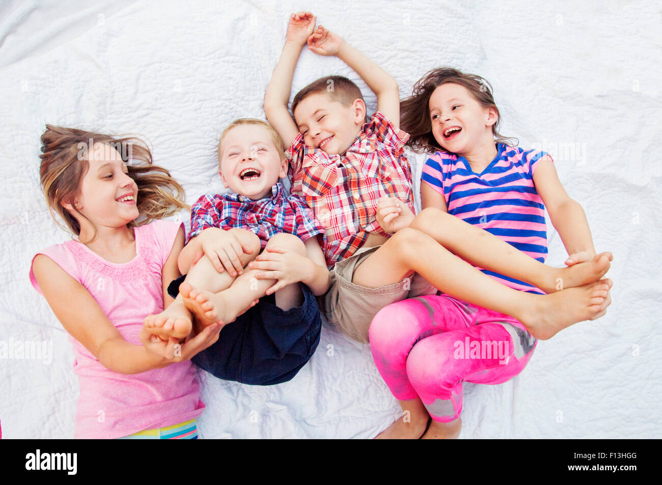 Two sisters tickle two brothers feet Stock Photo