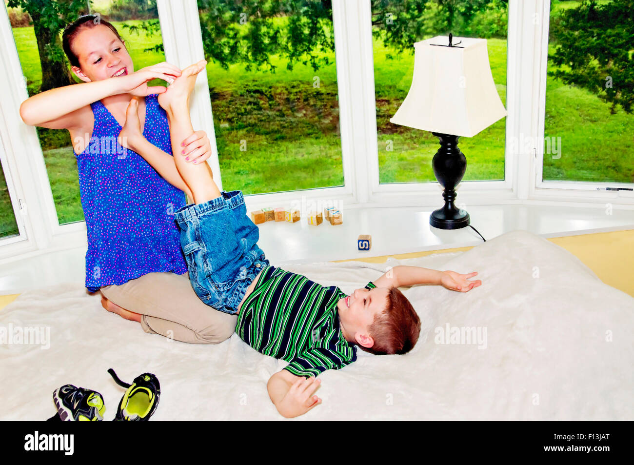 Girl lifts brothers foot to tickle Stock Photo