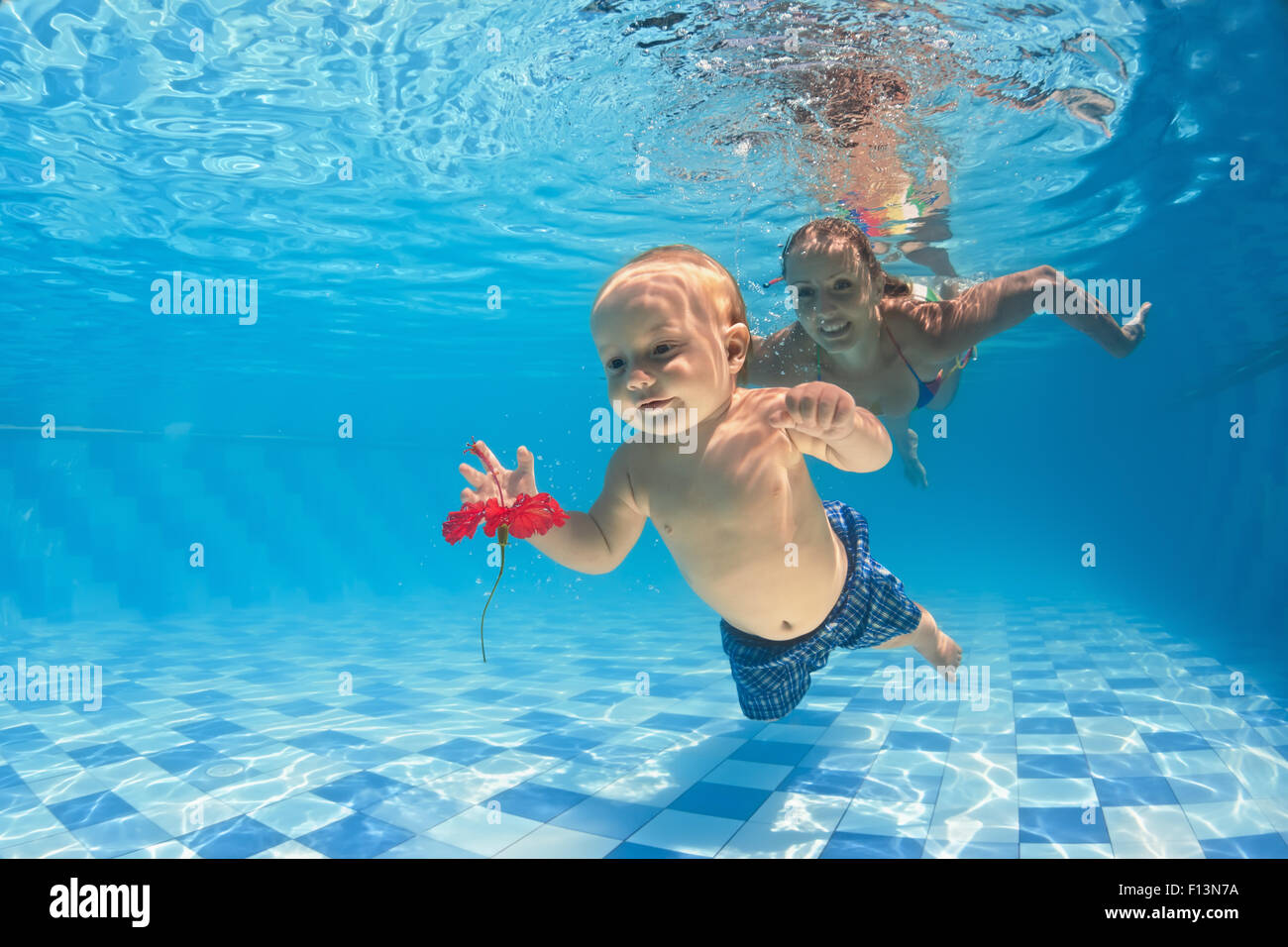 Young mother teaches to swim 10 month old baby dive with cheerful