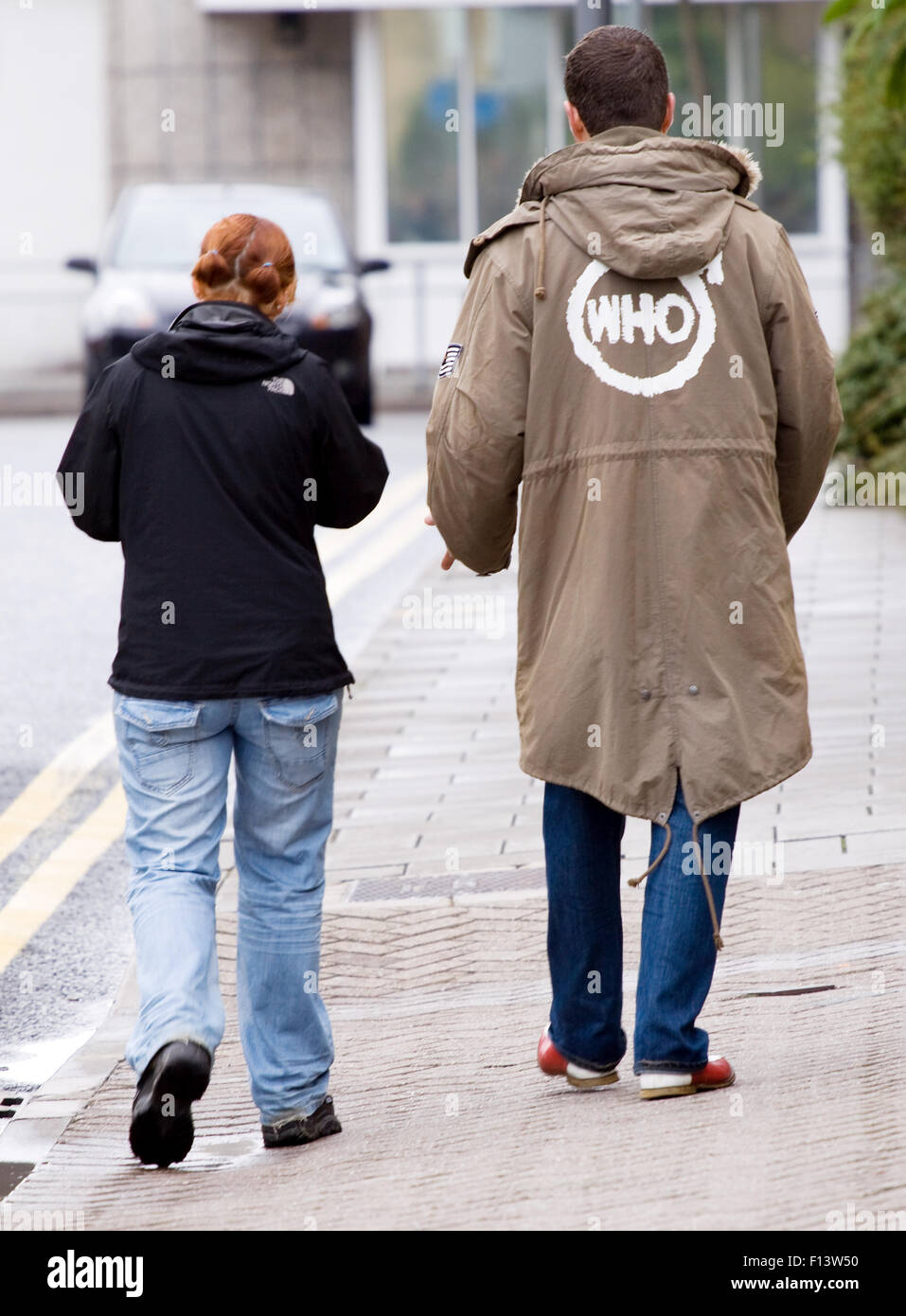 A mod, dressd in 60's mod clothing walking along a street. He has a logo  for the band, The Who, painted on the back of a Parka coat Stock Photo -  Alamy