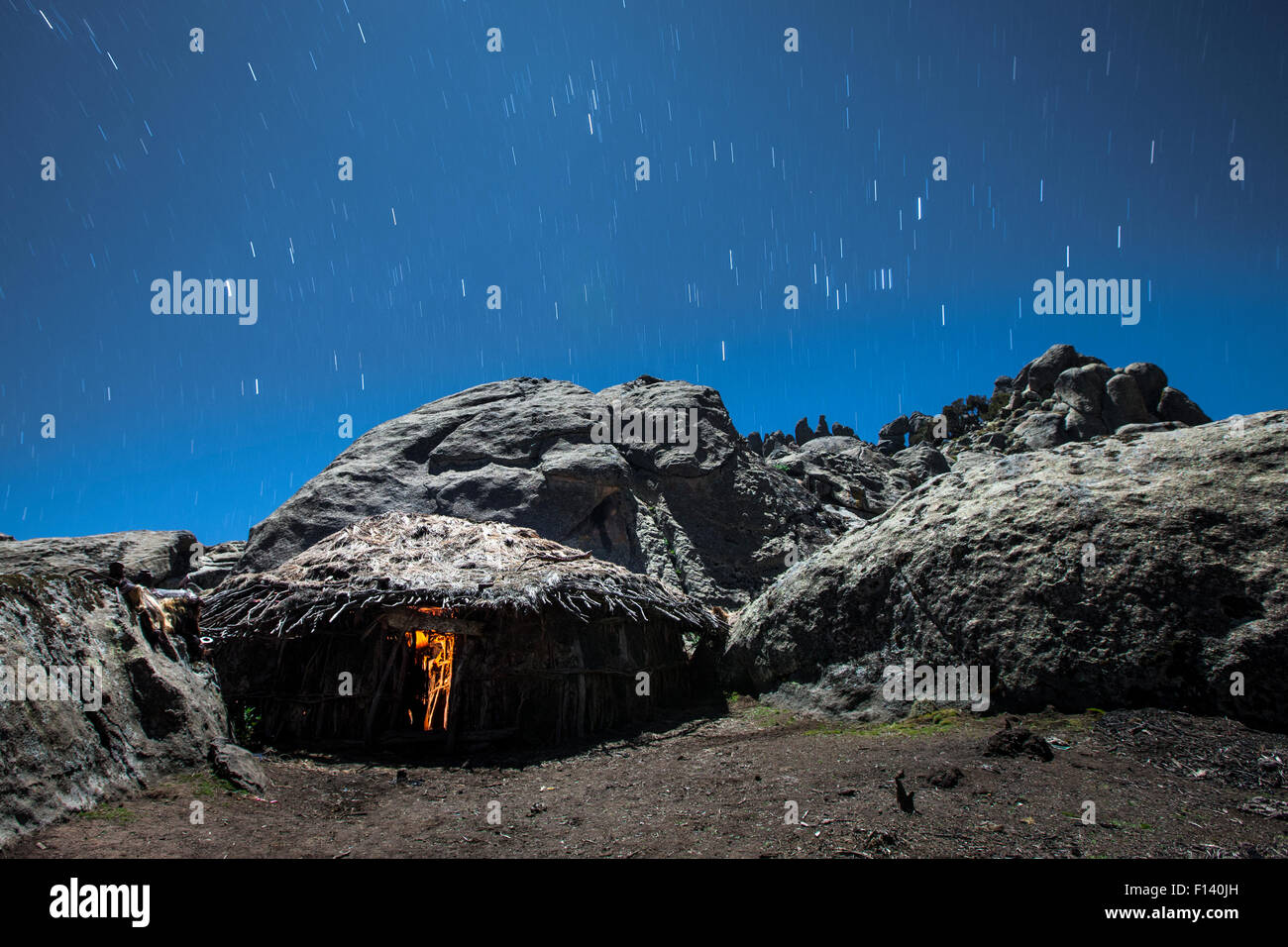 Cooking hut lit inside by a small cooking fire, with star trails, Bale Mountains National Park, Ethiopia, December 2011. Stock Photo