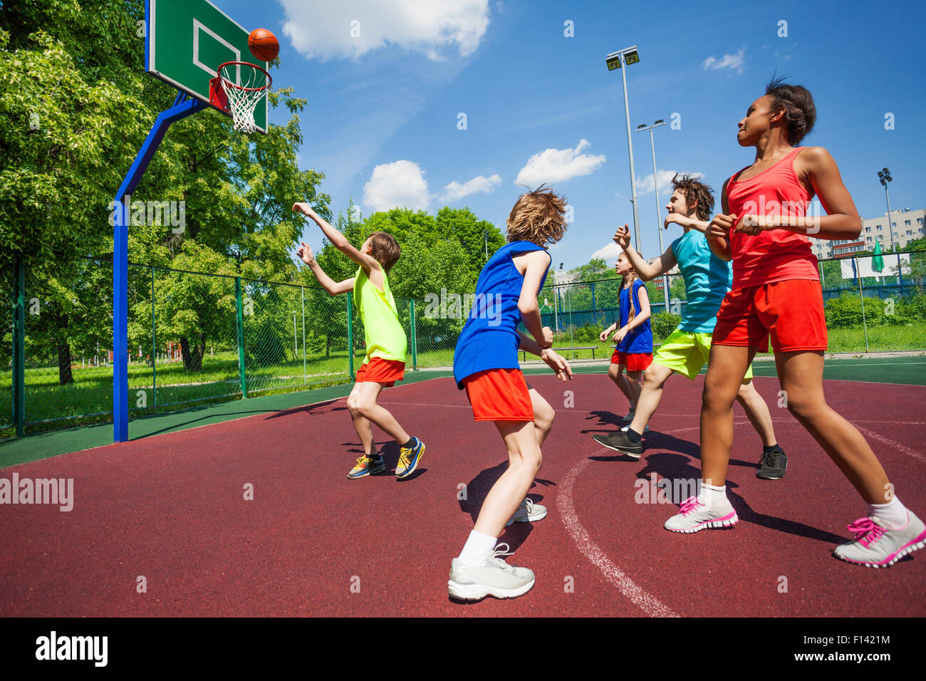 Teenagers in colorful uniforms playing basketball Stock Photo