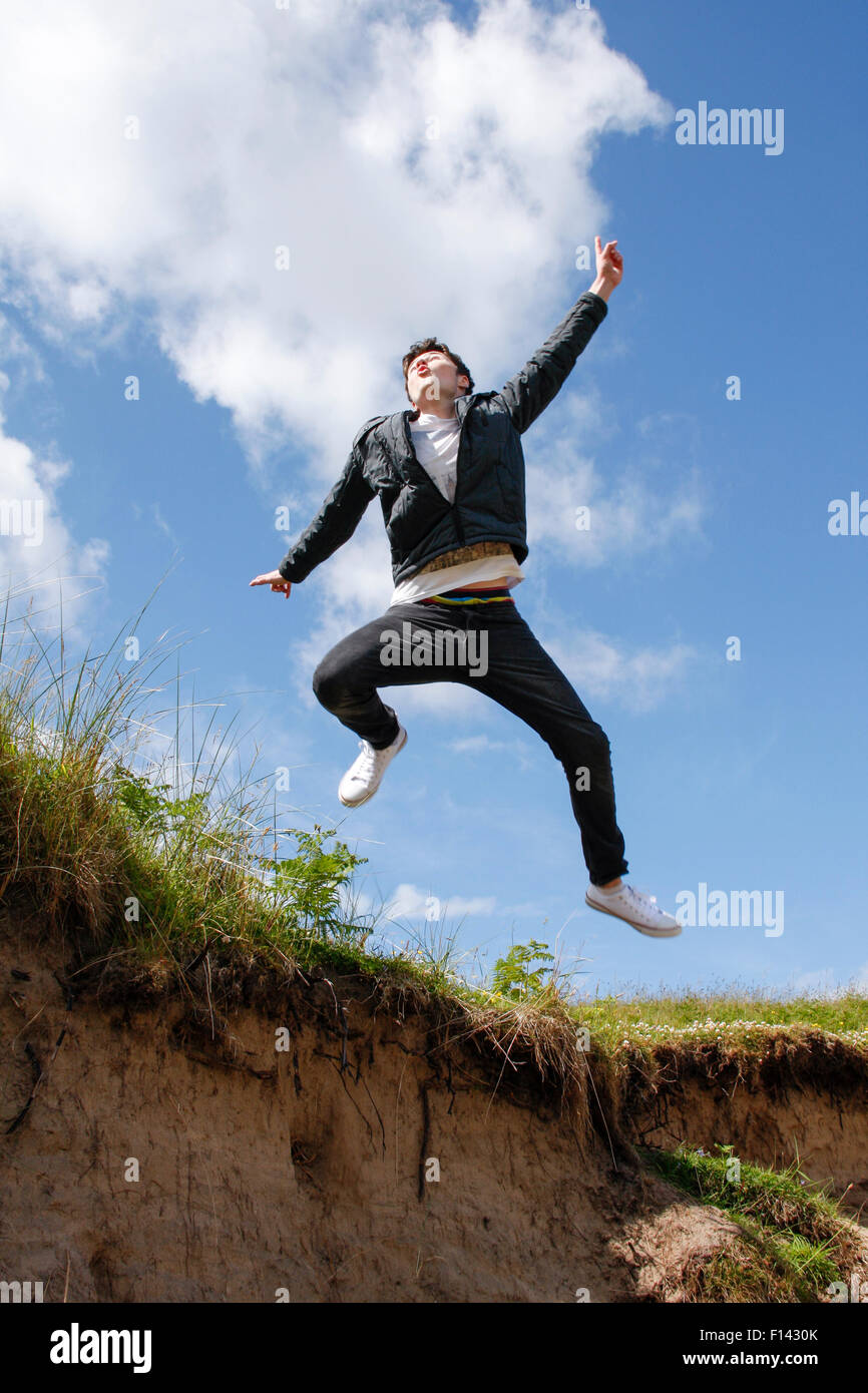 Happy teenage caucasian boy jumping in air displaying happiness, joy, excitement, delight, exhilaration Stock Photo