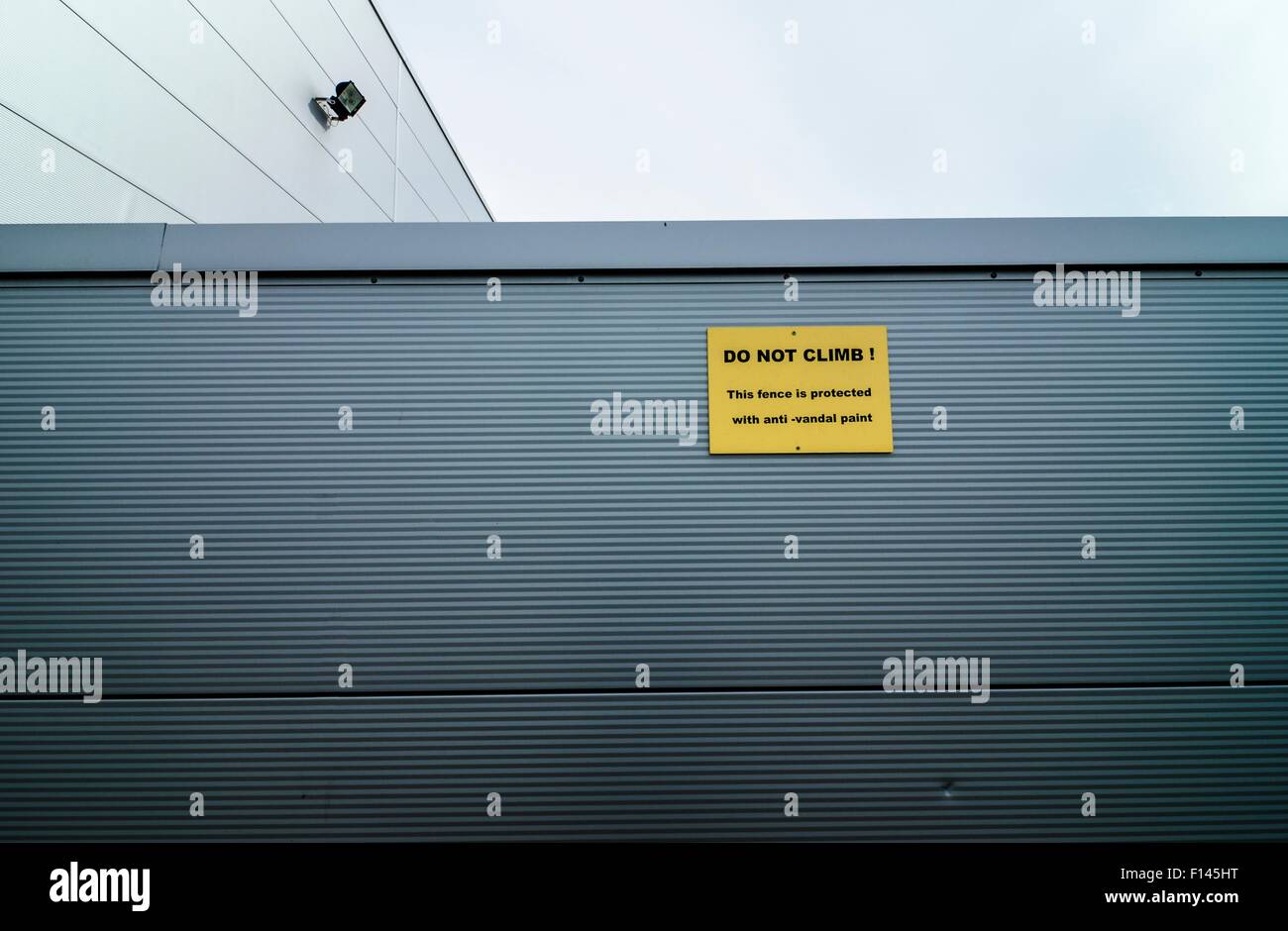 Metal clad industrial building with sign warning of anti-vandal paint. Anti-vandal paint uses a non-drying oil so that it remains permanently greasy and slippery, and leaves marks on intruders. Stock Photo