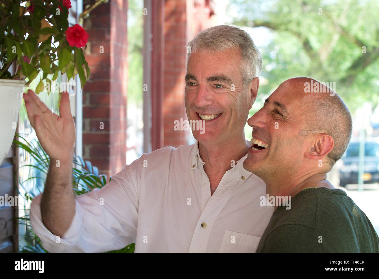 Gay senior male couple, smiling and laughing, on vacation and window shopping in small village Stock Photo