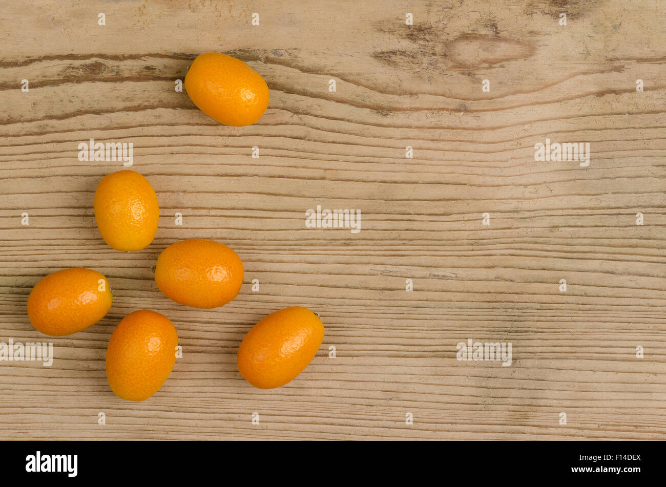 Oval kumquats on old spruce wood board. Closeup. Macro photo from above. Stock Photo