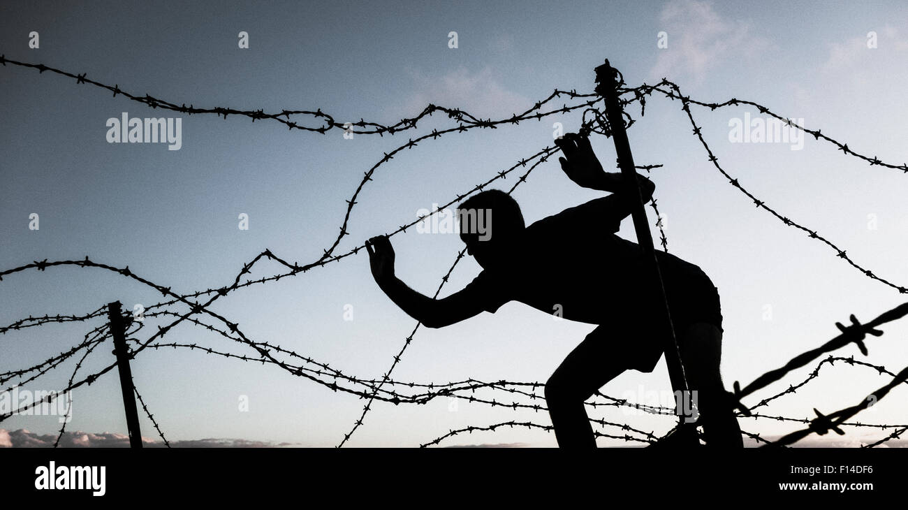 Man looking through barbed wire fence at sunset. Model released Brexit/ immigration/refugee... concept image. Stock Photo