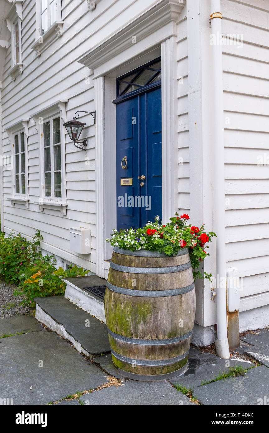 Large wine or beer barrel used as a standing flower pot outside a traditional Norwegian timber built house in Stavanger old town Stock Photo