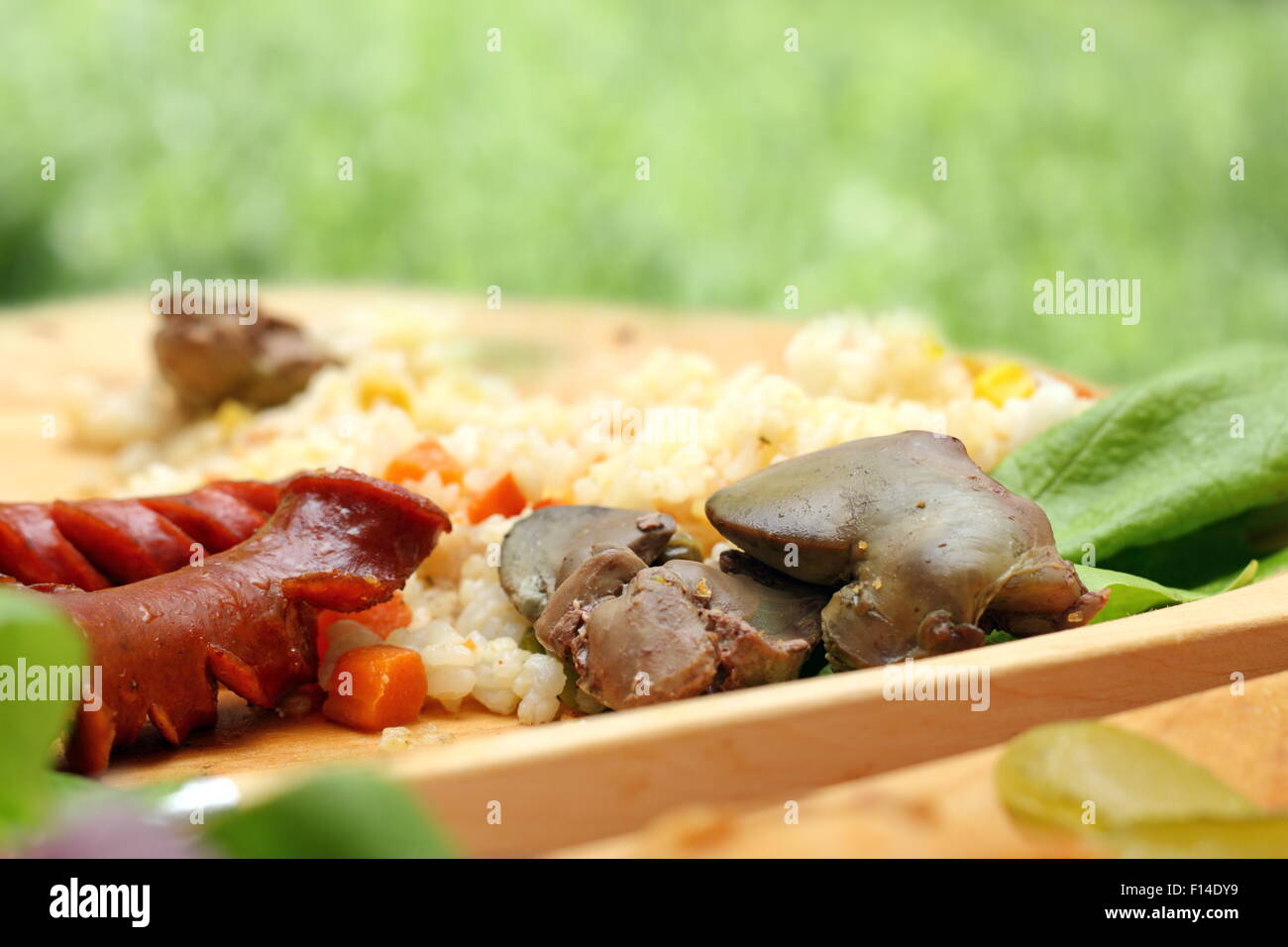 chicken liver and pork sausages served with green salad on wooden plate Stock Photo