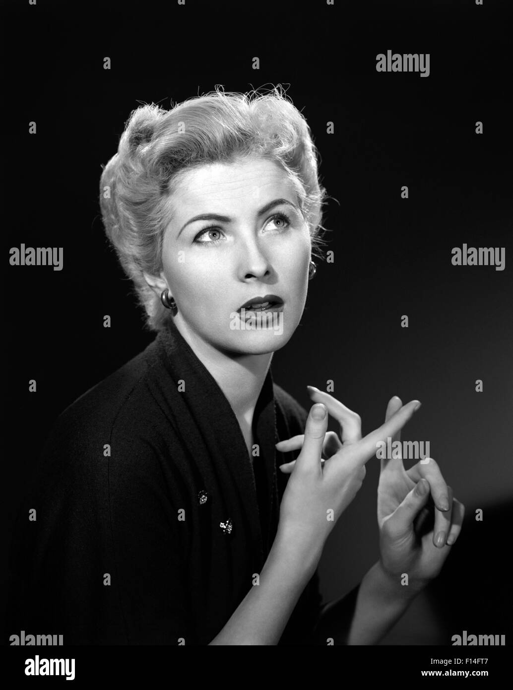 1950s THOUGHTFUL BLOND WOMAN COUNTING ON HER FINGERS LOOKING AWAY Stock Photo