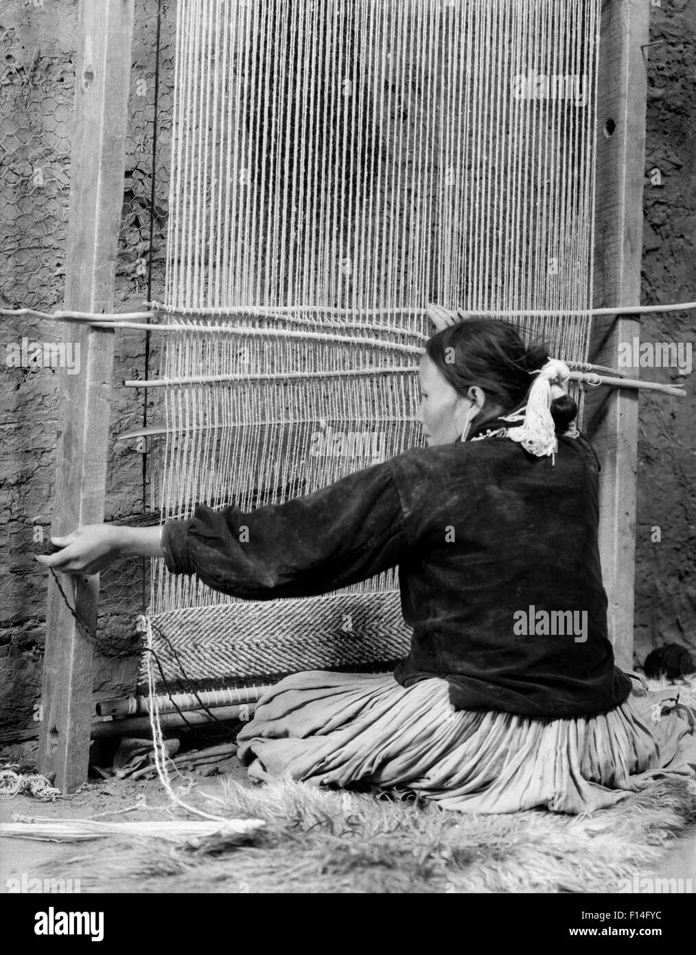 1930s NATIVE AMERICAN NAVAJO WOMAN SEATED AT LOOM WEAVING A RUG Stock