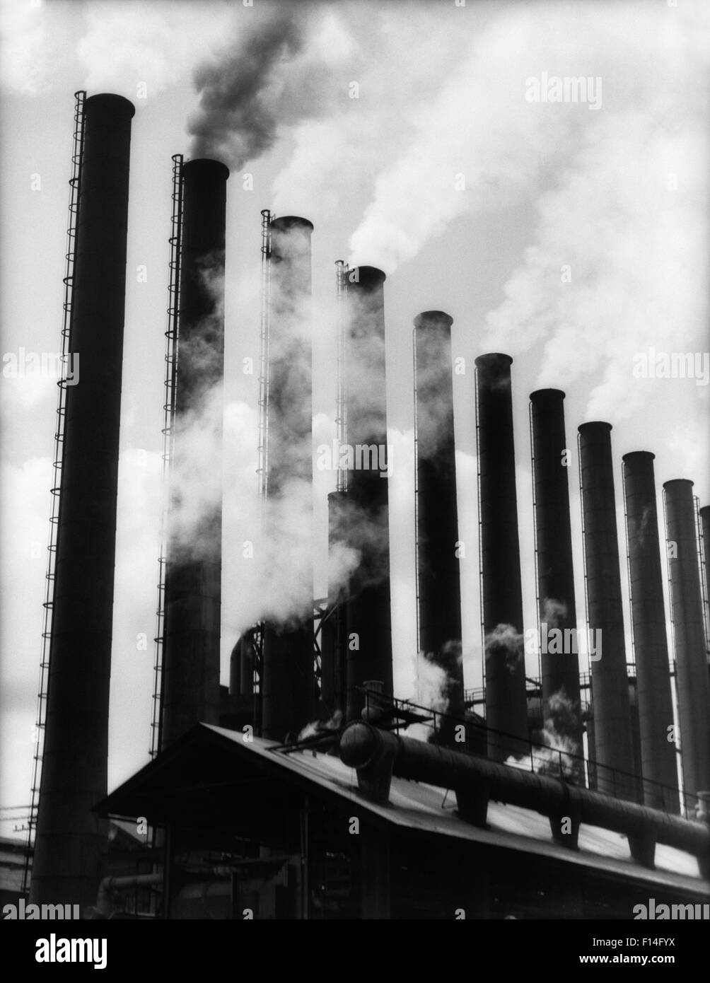 1930s SMOKE STACKS AT FACTORY THEN SYMBOL OF PRODUCTION NOW SYMBOL OF POLLUTION Stock Photo
