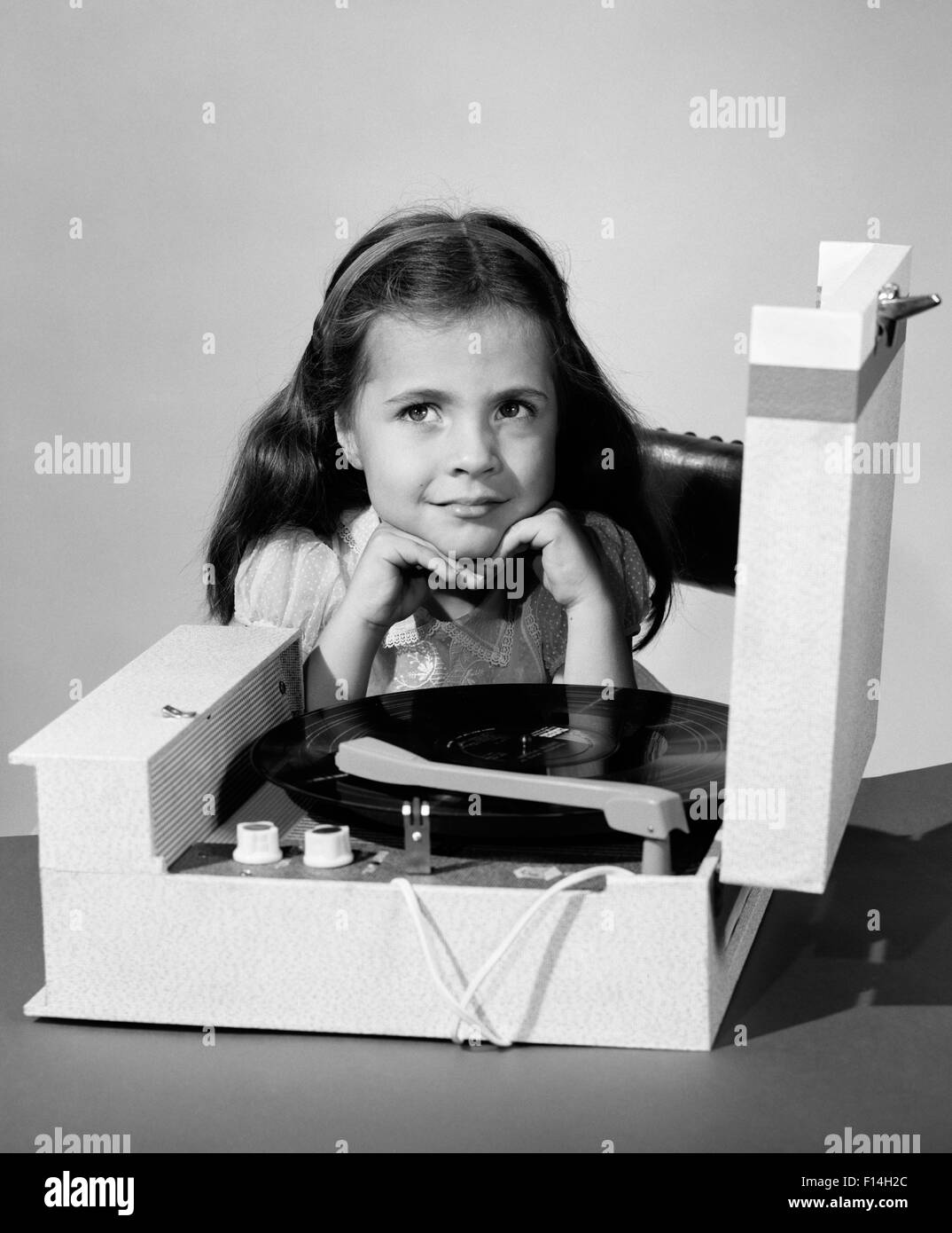 1960s SMILING JUVENILE GIRL LISTENING TO RECORD PLAYER 33RPM VINYL RECORD Stock Photo