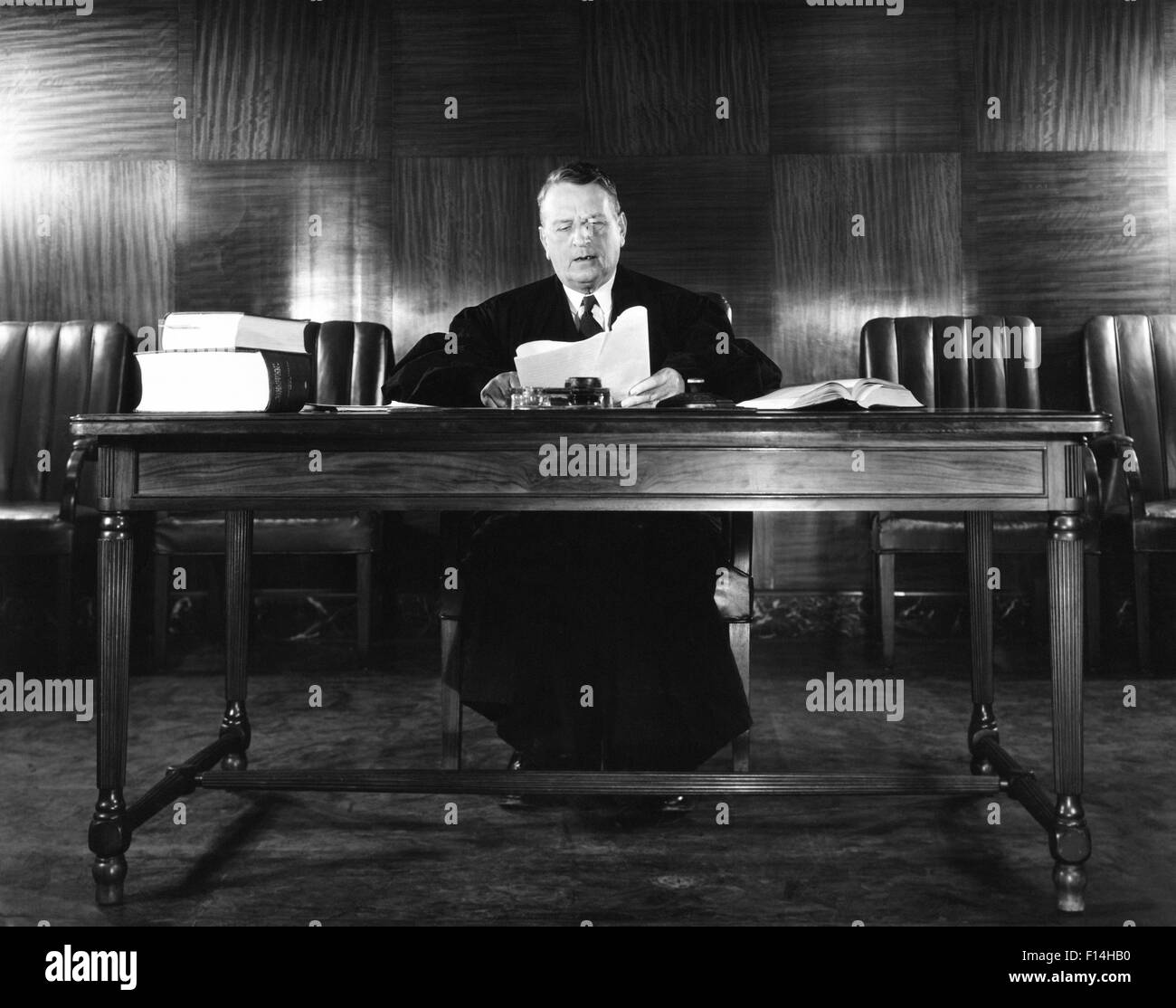 1940s MAN JUDGE READING PAPERS WEARING ROBE SEATED AT DESK Stock Photo