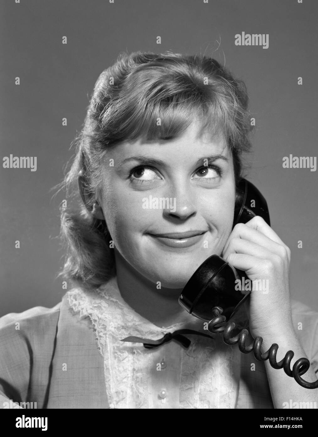 1950s 1960s TEENAGED GIRL TALKING ON TELEPHONE ROLLING EYES SMILING INDOOR Stock Photo