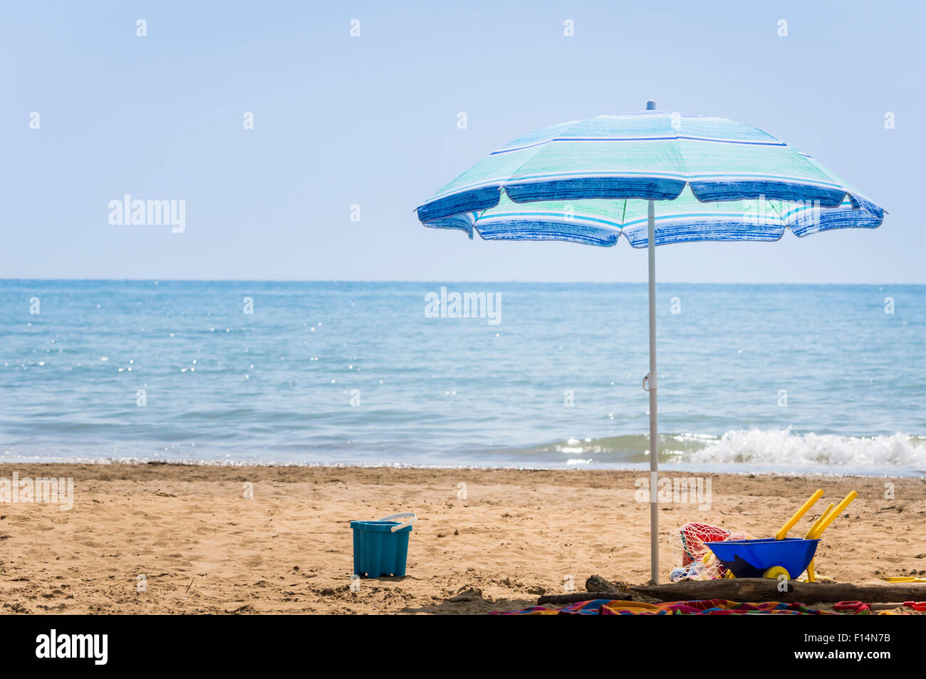 Umbrella beach and children beach toys on beach in summer day. Stock Photo