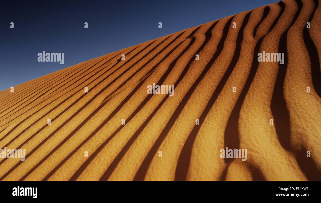 Low angle view of rippling desert sand dunes under blue sky Stock Photo