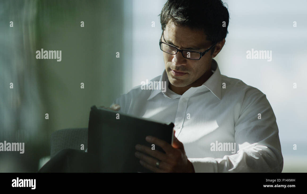 Serious businessman working on digital tablet at office desk Stock Photo