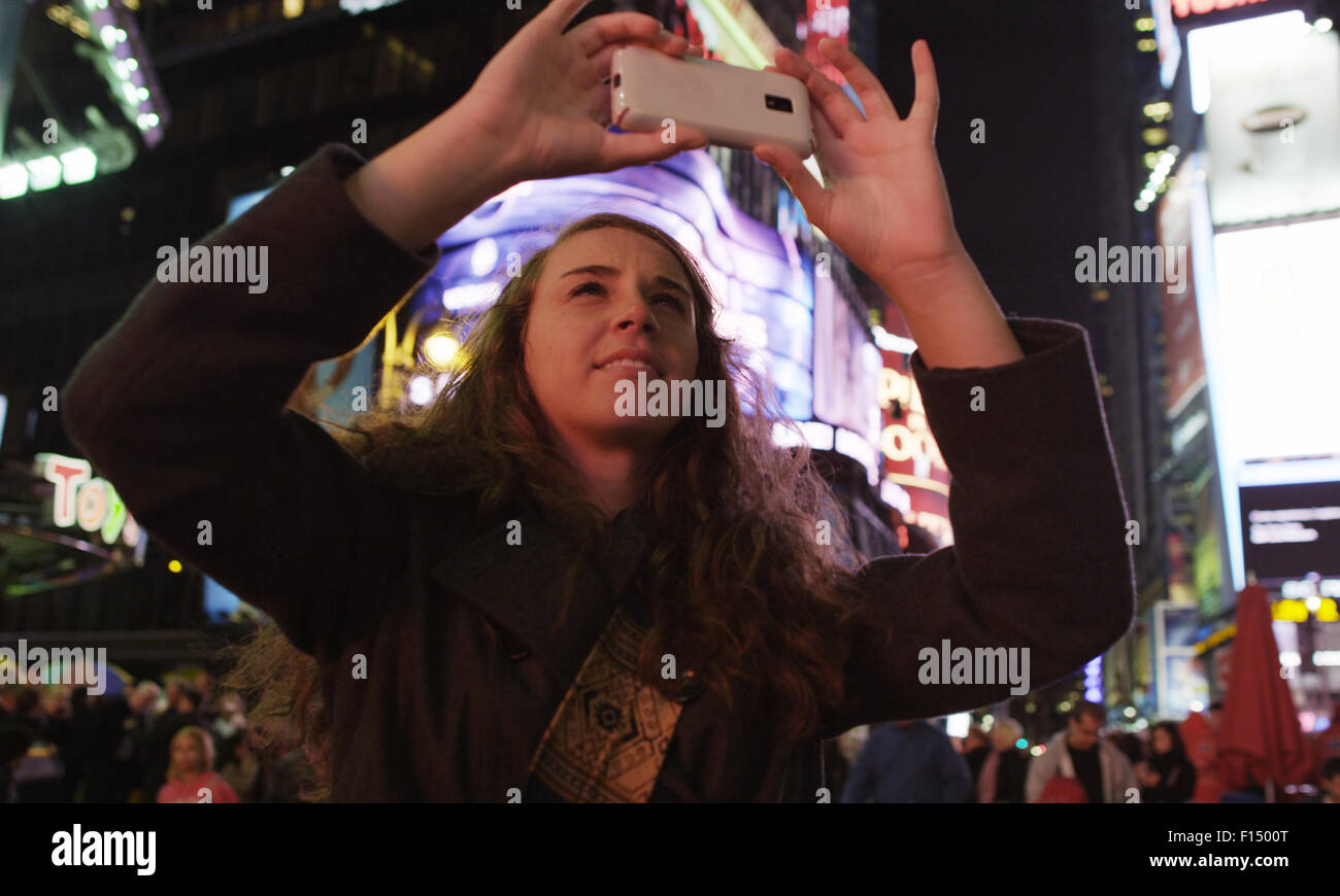 Woman taking photographs in Times Square, New York City Stock Photo