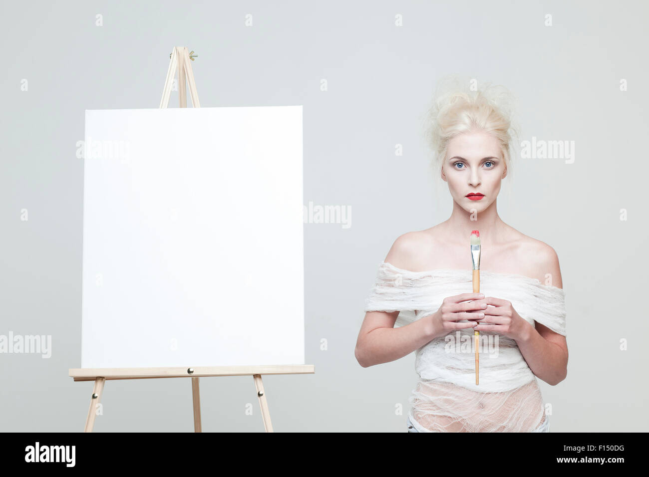 Studio portrait of young woman standing next to easel Stock Photo - Alamy