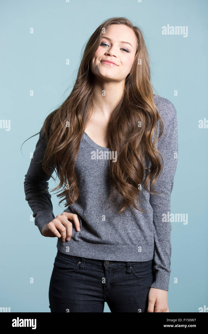 Three quarter length of happy woman with long brown hair and hand on hip Stock Photo