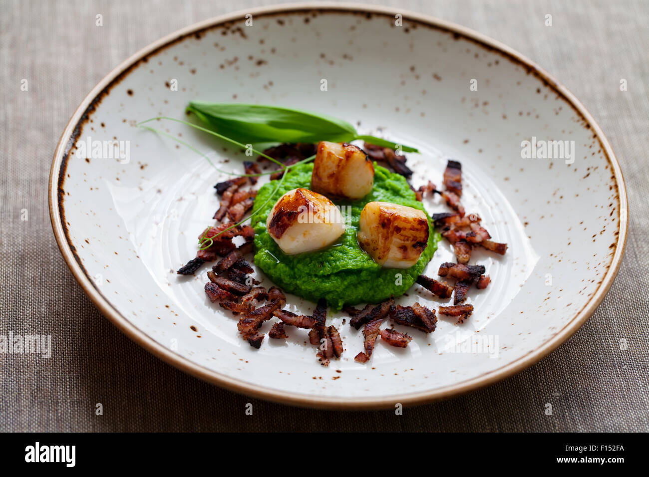 Scallops with pea puree and crispy bacon Stock Photo Alamy