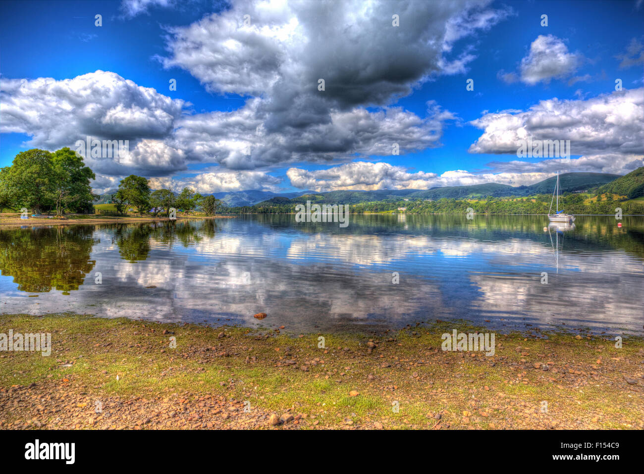 The British Lake District England UK at Ullswater with mountains and blue sky on beautiful summer day with reflections in HDR Stock Photo