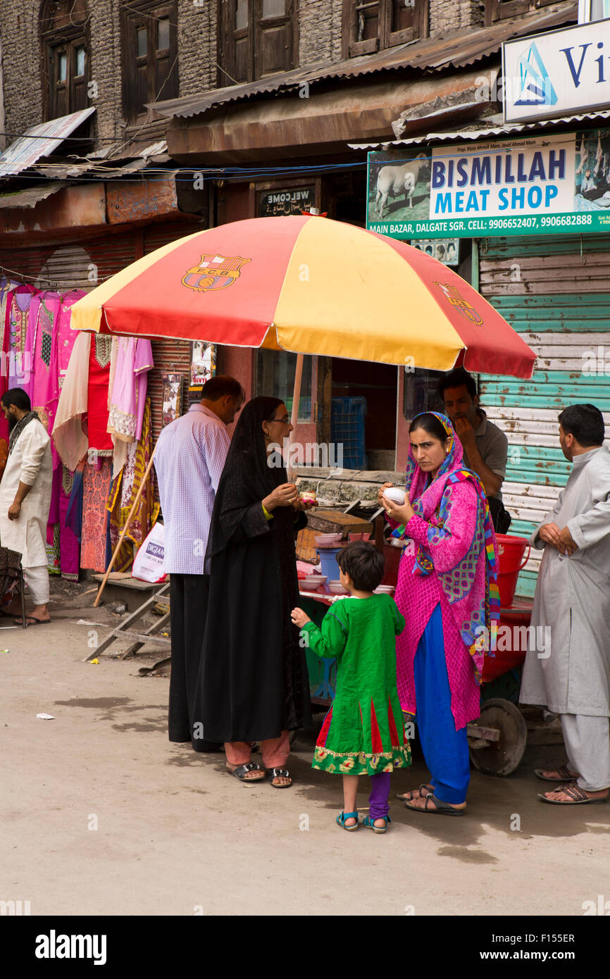 India, Jammu & Kashmir, Srinagar, Dalgate, colurfully dressed women eating ice cream under shade of umbrella Stock Photo