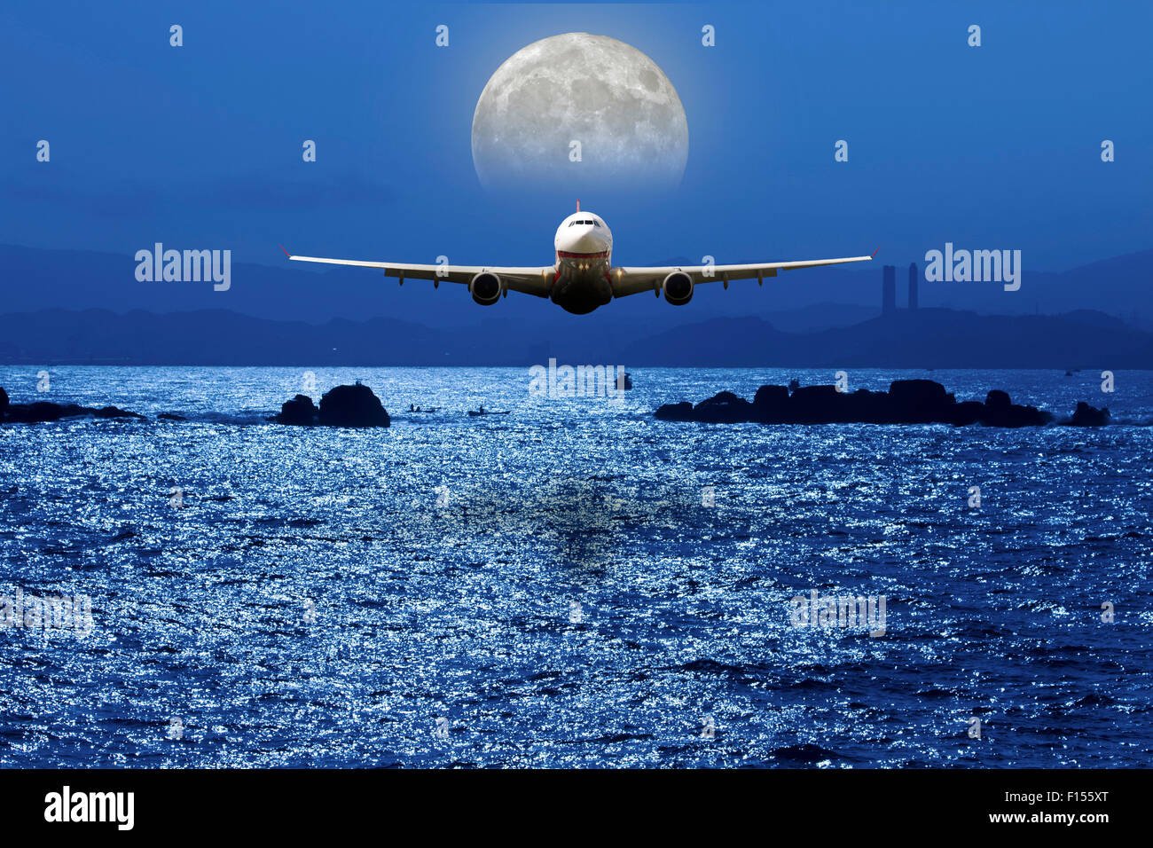 airplane fly above ocean under moonlight Stock Photo