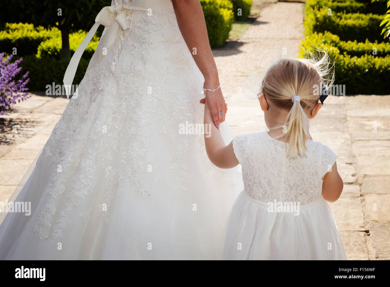 A bride holding the hand of her young bridesmaid at her wedding; UK Stock Photo