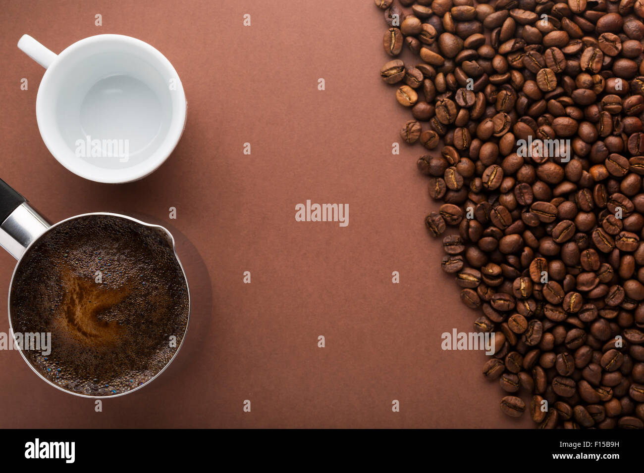 Pot of coffee, coffee beans and white empty cup on brown background. Top view. Focus on pot Stock Photo