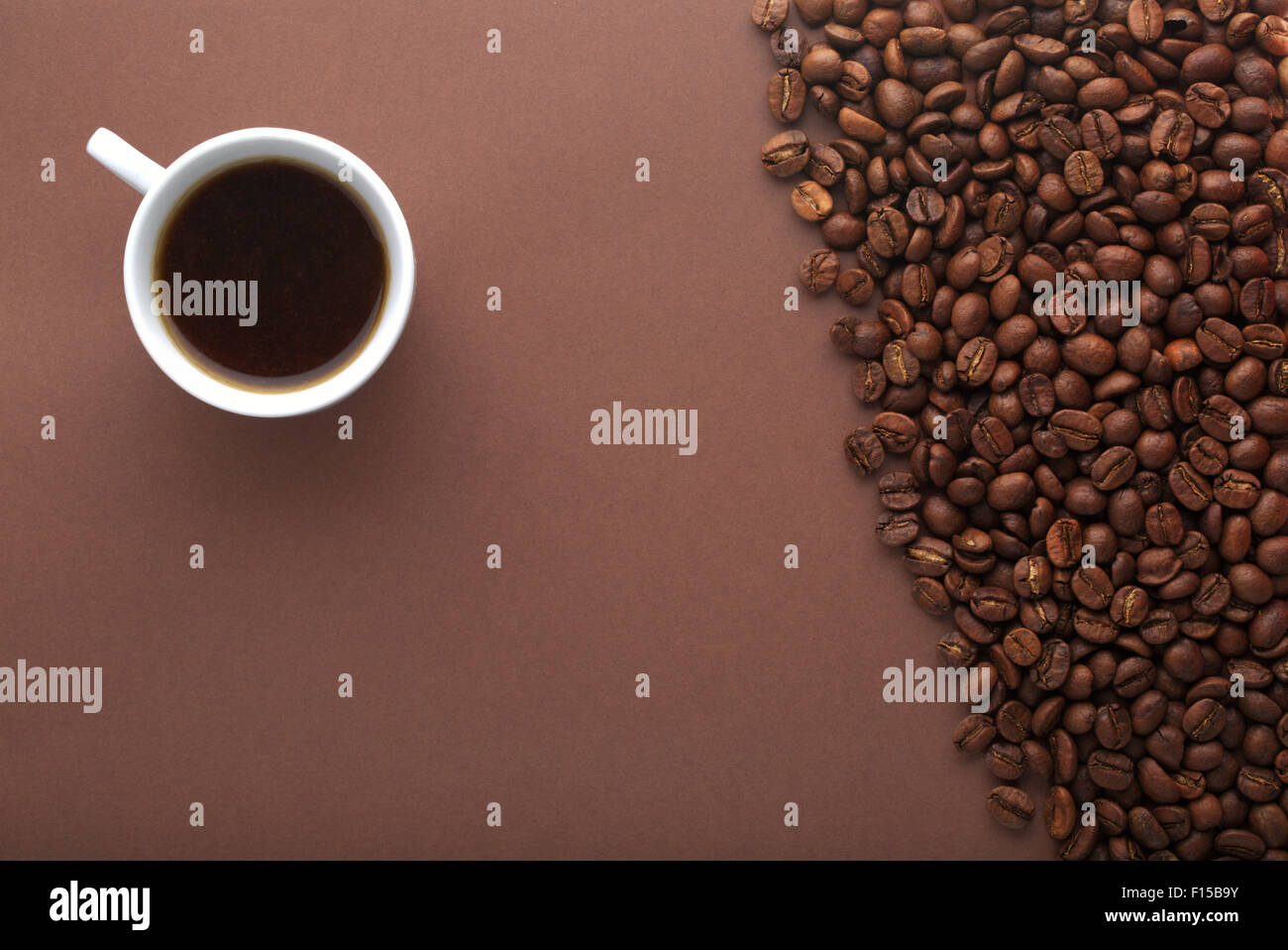 Hot coffee cup and beans on a brown background. Top view Stock Photo