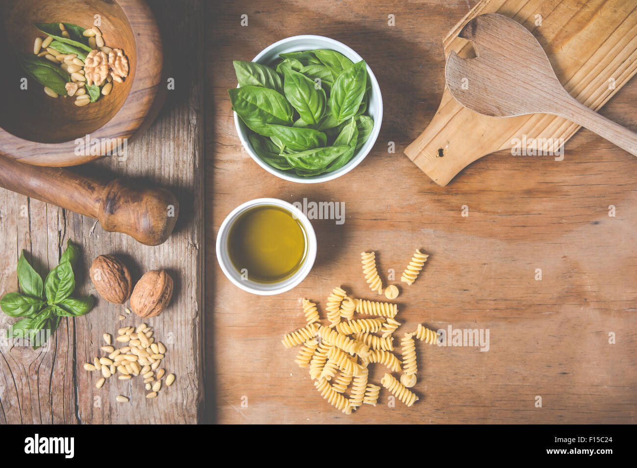 Making pasta with pesto with the original recipe of Genova. Wooden background and accessories communicate the sense of Italy. Stock Photo
