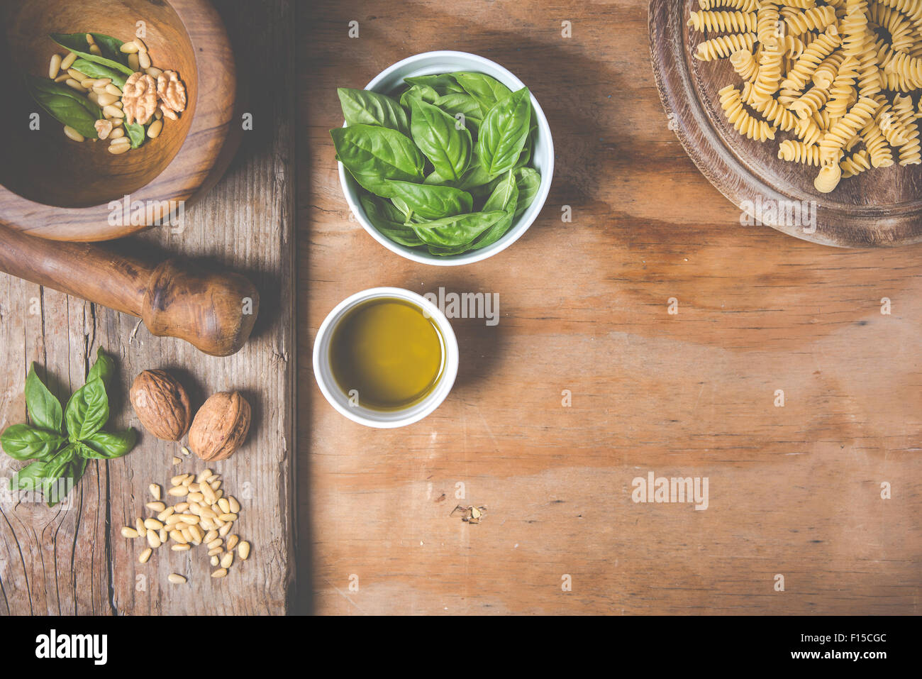 Making pasta with pesto with the original recipe of Genova. Wooden background and accessories communicate the sense of Italy. Stock Photo