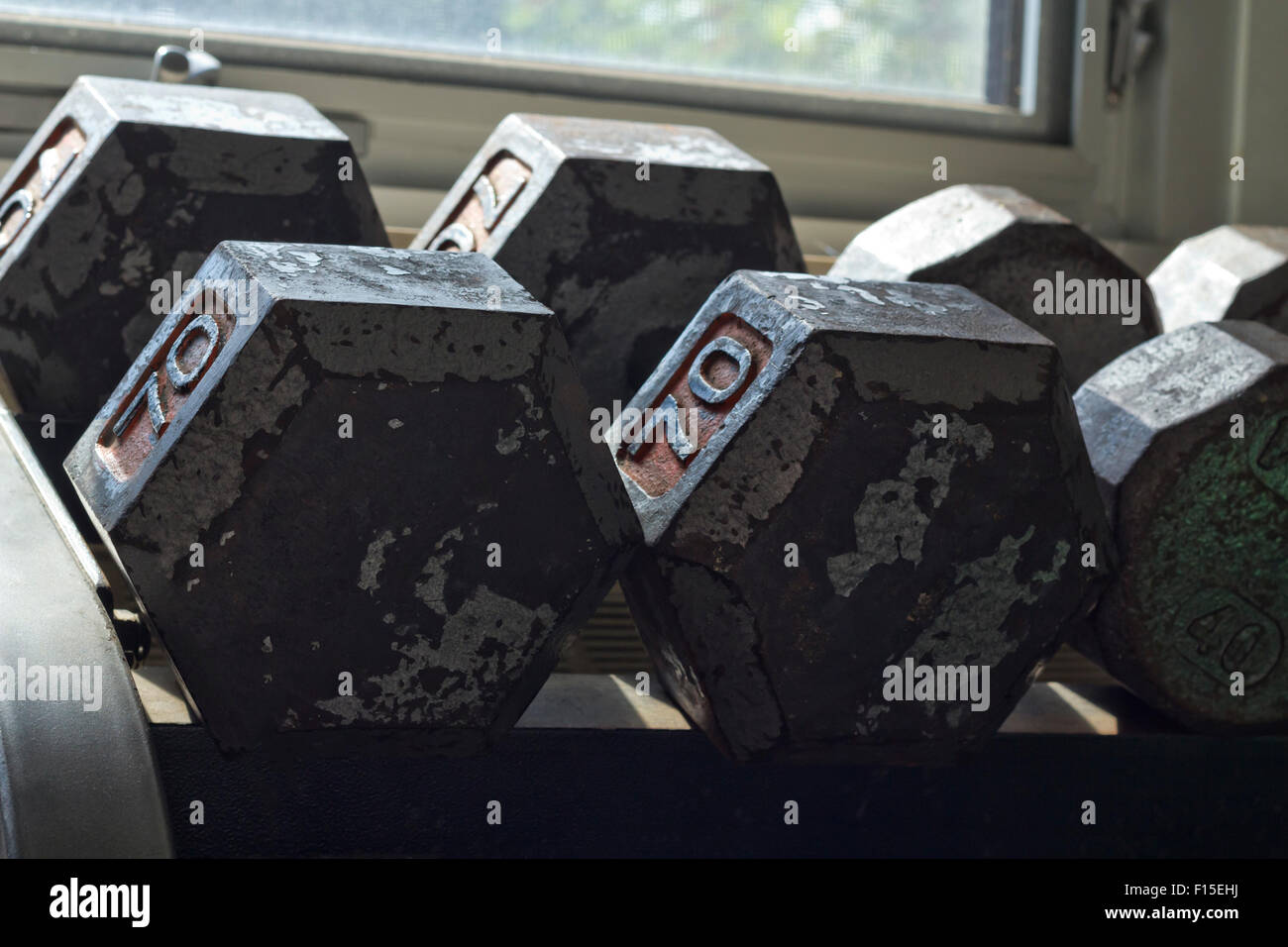 Various sizes and weights of used textured and old dumbbells at gym Stock Photo